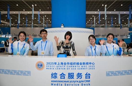 8月28日，可进行中、俄、英语互动的人形机器人“小合”与志愿者服务人员在综合服务台欢迎到访记者。新华社记者 孙凡越 摄